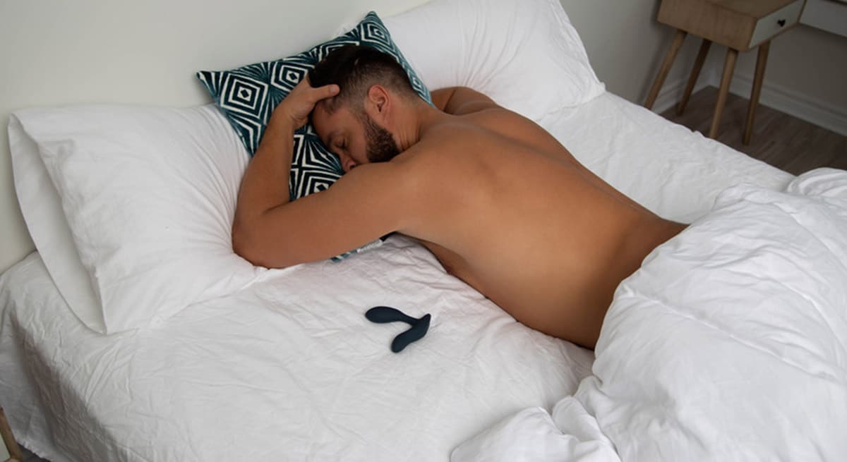 Mann ligger i sengen med prostatavibrator