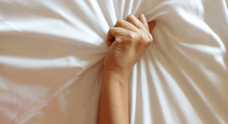 artikkel orgasmegapet hånd som holder i sengetøy