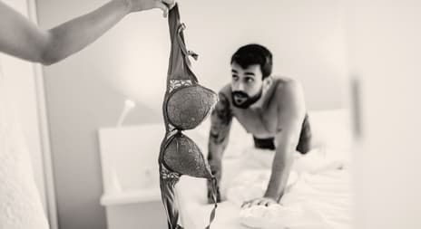 Erotiske noveller Mann på seng, kvinne holder BH