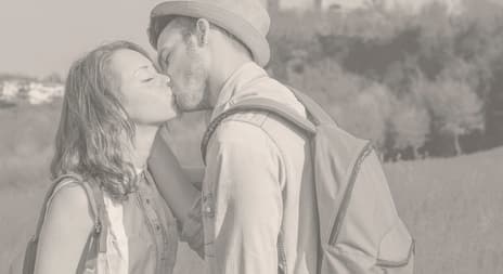 Ungt par kysser på en eng