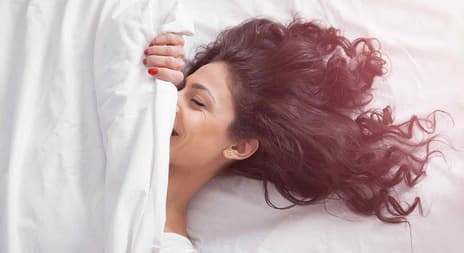 smilende kvinne ligger i seng